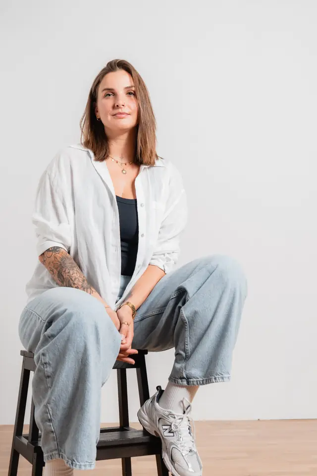 Kathy Alume, Webdesignerin, sitzt lächelnd auf einem Hocker